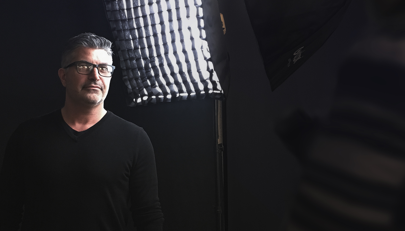 Man standing in front of a black background and a professional photographer's lamp