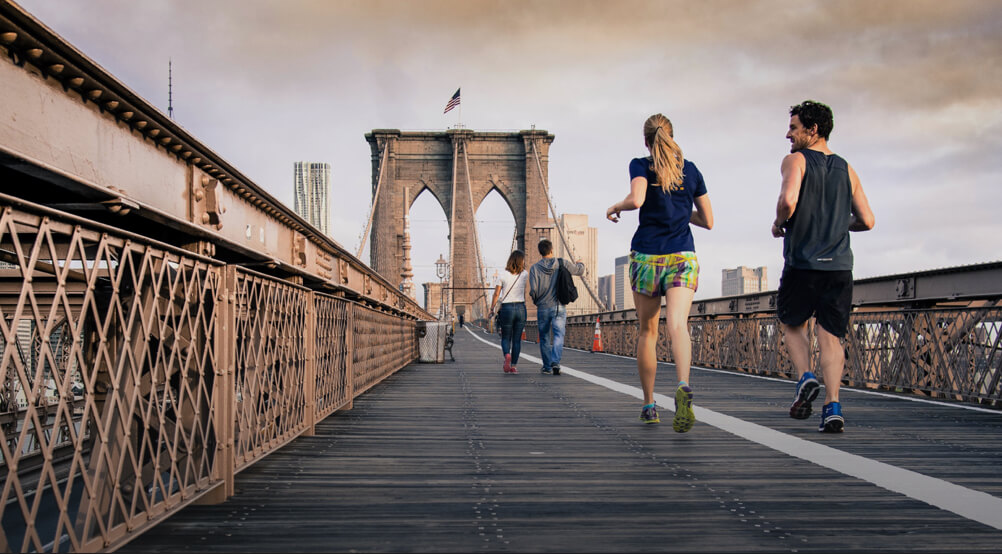Two people running across the Brooklyn Bridge
